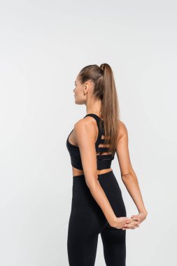 Spor sutyenli esmer sporcu kadın beyaz, sağlıklı ve formda bir konseptle ısınıyor.