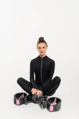 boots for jumping, sportswoman in black jumpsuit sitting with crossed legs, kangoo jumping,  clipart