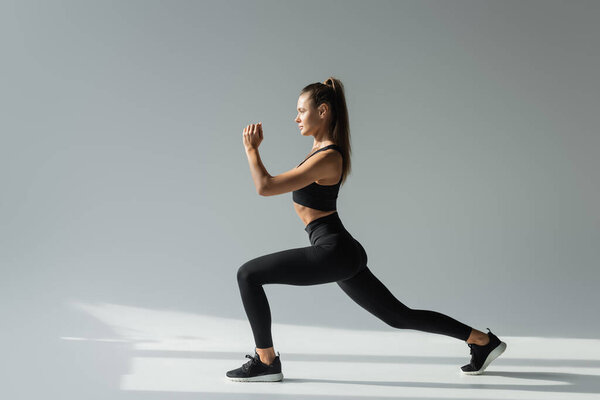 fit brunette sportswoman in black sports bra and leggings doing lunges active lifestyle concept