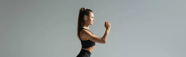 stock image Side view of brunette fit sportswoman working out on grey, banner, active lifestyle concept