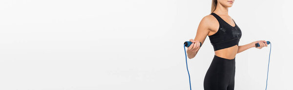 cropped view of fit sportswoman holding jump rope isolated on white, banner, healthy and fit concept