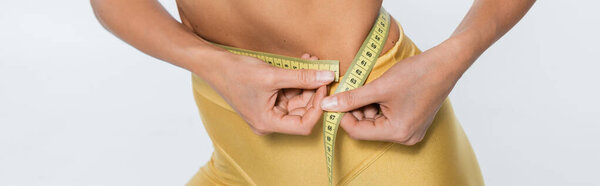 weight loss, cropped view of woman measuring waist with tape on white background, body size, banner