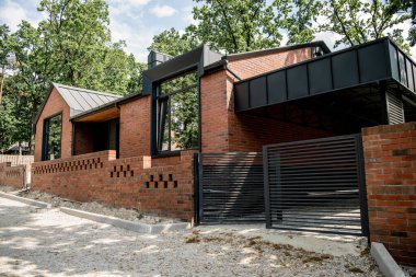 housing trends, brick contemporary house with metal gates and brick fence clipart