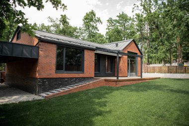 modern brick house with large windows, green lawn, cottage town clipart