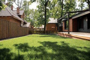 verandalı, yeşil çimenlikli, ahşap çitli, kır evi olan, emlak piyasası olan modern bir ev.