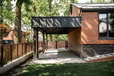 Verandası ve yeşil ağaçların altında çimenliği olan rahat bir ev köy kasabası, emlak piyasası.