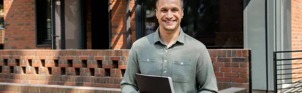 stock image successful and confident real estate broker smiling at camera near contemporary cottage, banner