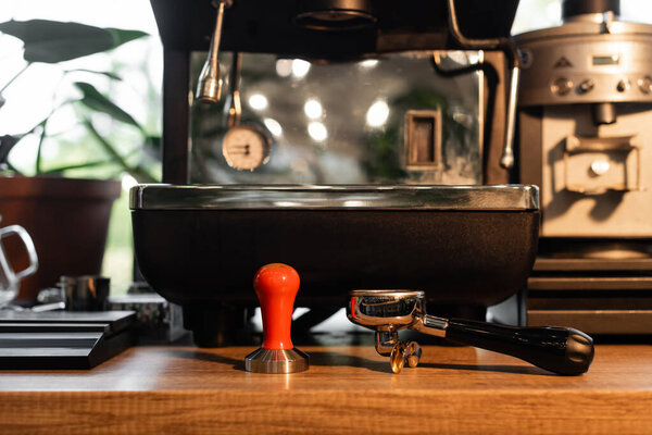 holder and press on worktop near blurred coffee machine in coffee shop on background