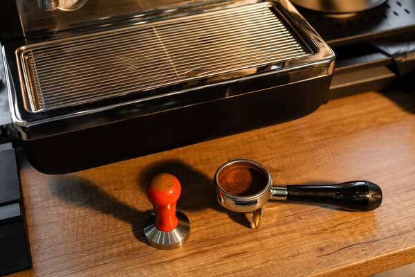 high angle view of press and coffee in holder on worktop near coffee machine in cafe