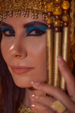 Portrait of beautiful woman with bold makeup and traditional egyptian headdress looking at camera clipart