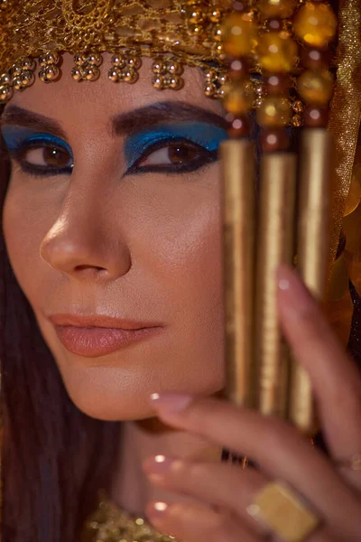 Portrait of beautiful woman with bold makeup and traditional egyptian headdress looking at camera