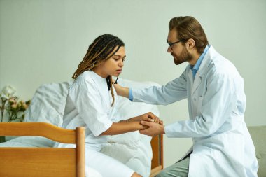 Afrikalı Amerikalı bir kadının elini tutan erkek doktor. Rahatlatıcı bir hasta, özel koğuş, hastane.