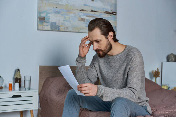 man holding ultrasound photo, sitting on bed, pregnancy, responsibility, making decision, worried
