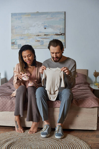 happy african american woman holding tiny baby shoes, future mother, expectation, awaiting