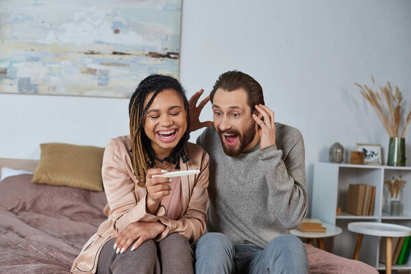 cheerful interracial couple holding pregnancy test, future parents, african american woman and man