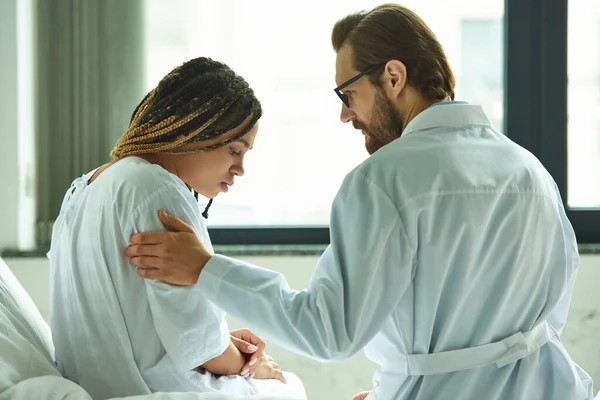 stock image doctor comforting upset african american woman, touching shoulder, private ward, miscarriage