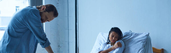 концепция выкидыша, депрессивная африканская женщина лежит в больничной койке рядом с мужем, баннер