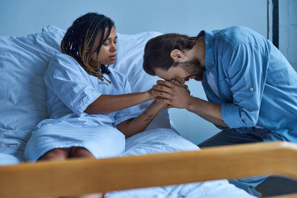Концепция выкидыша, грустная африканская американка, держащая за руку скорбящего мужа, больничную палату