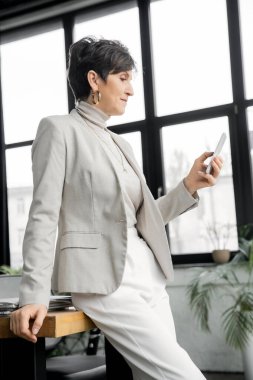 confident woman, executive manager, messaging on smartphone in office, stylish business casual clipart