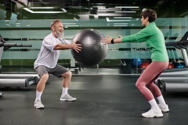 Mutlu yaşlı adam ve kadın spor salonunda fitness topu, aktif yaşlılar, çift sporu