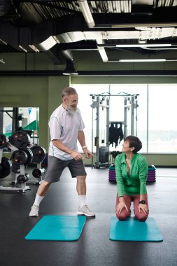 Fitness paspaslarının yanında mutlu yaşlı bir çift, birbirlerine bakıyorlar, uzun boylu, aktif yaşlılar, sportif.