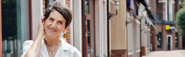 старение населения, кавказский, счастливый, пожилая женщина регулируя короткие волосы, городской фон, улыбка, баннер