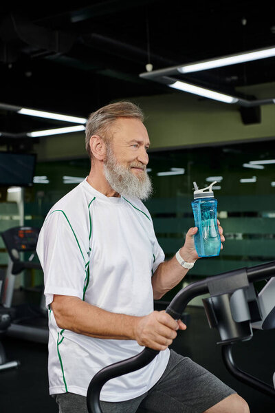 happy senior and bearded man holding sports bottle with water and looking away, sport, gym, work out