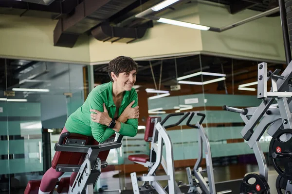 stock image happy elderly woman with short hair working out in gym, active, motivation, exercise machine