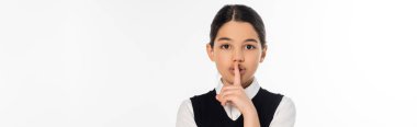 schoolgirl showing hush sign and looking at camera isolated on white, shh, finger near lips, banner clipart