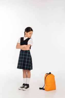 Kollarını kavuşturmuş, sırt çantasına, boyuna, okul konseptine bakan hoşnutsuz liseli kız.