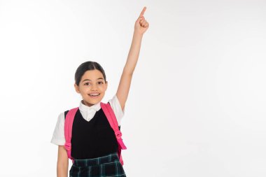 Okul üniformalı mutlu bir kız bir şey gösteriyor, parmağıyla işaret ediyor, beyaz, öğrenci.