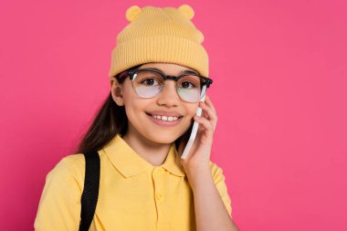 Bereli mutlu ve şık kız kameraya bakıyor, gözlüklü kız akıllı telefonla konuşuyor, pembe.
