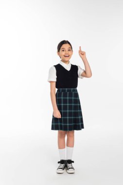 full length, positive schoolkid in uniform pointing up and looking at camera on white, girl in skirt clipart