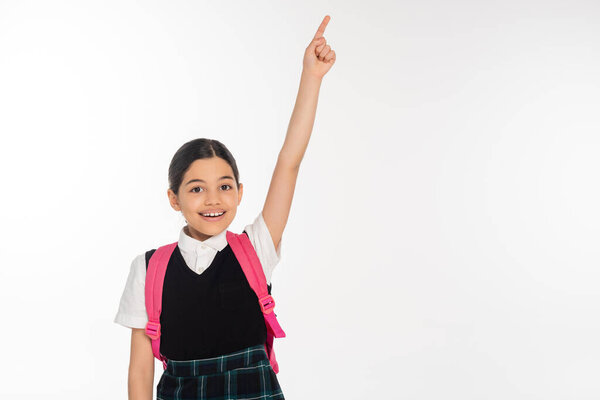 счастливая девушка в школьной форме показывает что-то, указывая пальцем изолированы на белом, студент