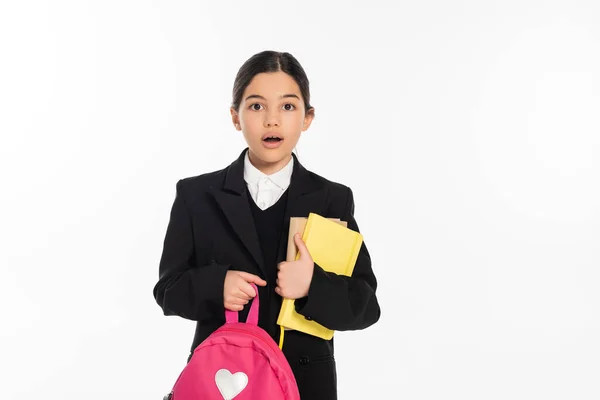 stock image shocked schoolgirl standing with notebooks and backpack on white, back to school concept