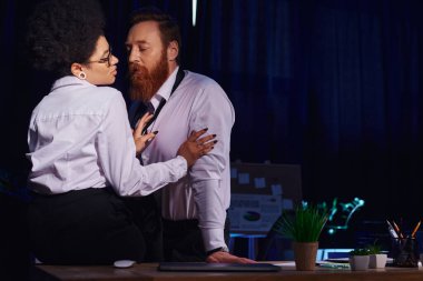Çekici Afrikalı Amerikalı kadın gece ofisinde iş masasında sakallı işadamını baştan çıkarıyor, romantizm