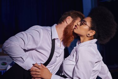 Sakallı iş adamı, gözlüklü seksi Afrikalı Amerikalı kadını kucaklıyor, ofiste romantik bir karşılaşma.