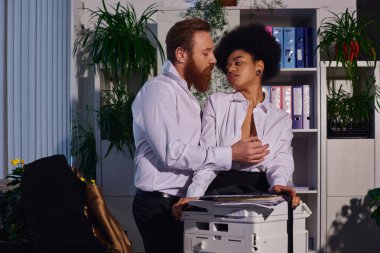 bearded businessman seducing and undressing young african american secretary near copier in office clipart