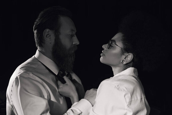 alluring african american woman tempting bearded businessman in night office, black and white image