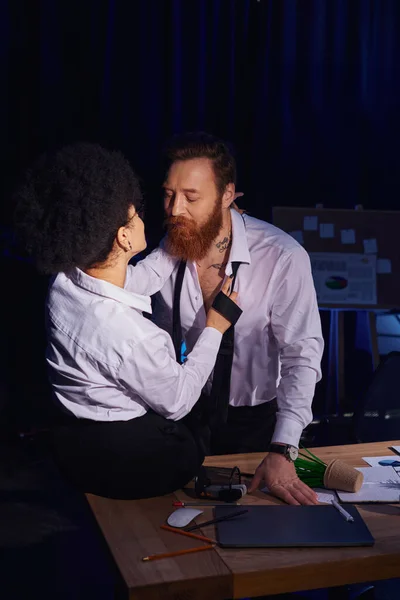 stock image hot african american woman seducing bearded tattooed colleague near mess on work desk in office