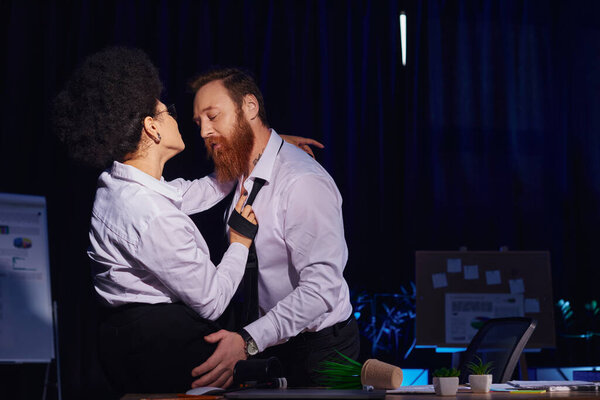 african american woman flirting with bearded tattooed colleague near mess on work desk in office
