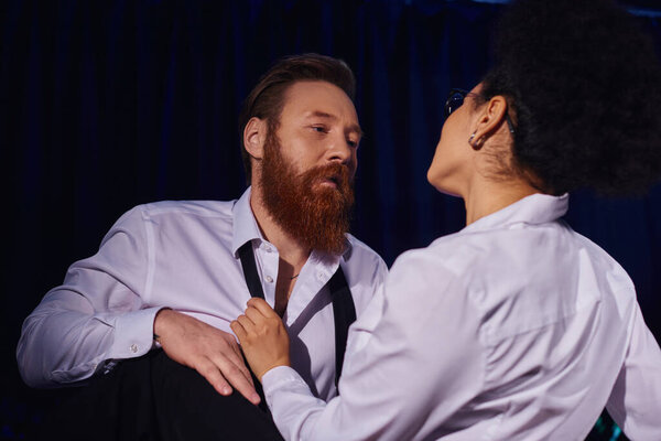 bearded businessman with seductive gaze tempting african american woman, secret love in night office