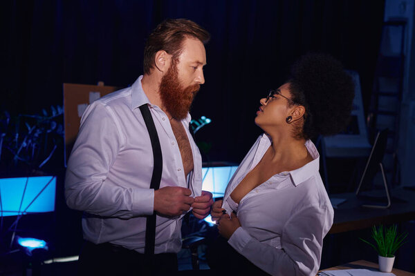 bearded businessman and african american woman undressing and looking at each other, side view