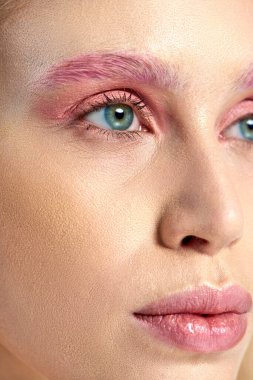 Mavi gözlü ve pembe göz makyajlı genç bir kadının detaylı fotoğrafı.