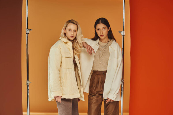 fall fashion, young interracial models in autumn clothes posing on pastel multicolored backdrop
