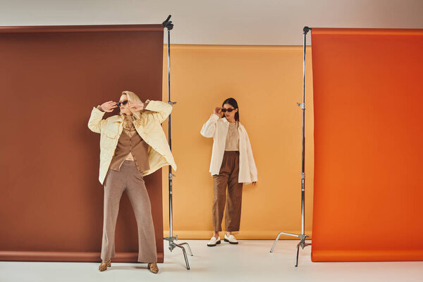 осенний сезон, мультиэтнические модели в солнцезащитных очках и осенняя одежда позируют на красочном фоне