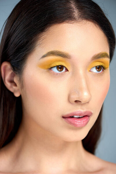 крупный план женщины с смелым макияжем, отводящим взгляд на синий задник, красоту и молодость