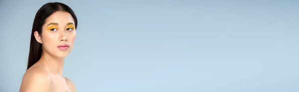 portrait, asian woman with bold makeup and bare shoulders looking away on blue backdrop, banner