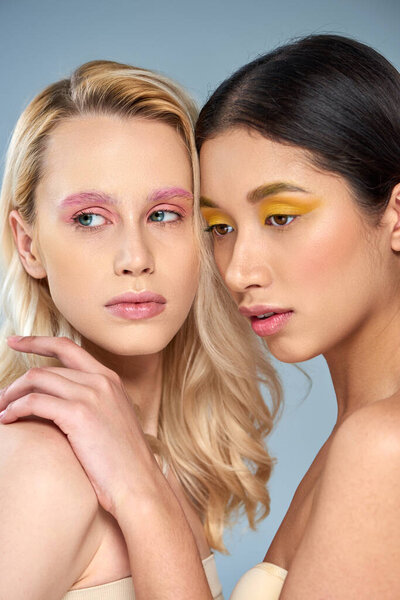 разная красота, портрет двух мультикультурных моделей с смелым макияжем, позирующим на синем фоне