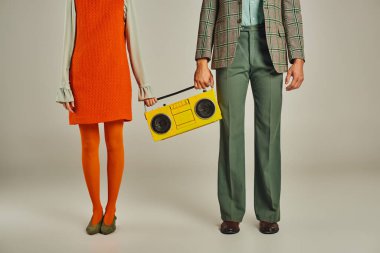 Renkli elbiseli çiftin gri renkli, klasik yaşam tarzında sarı boombox 'larıyla duruşu.